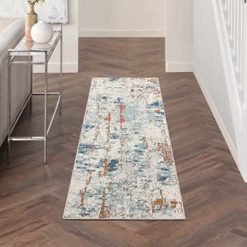 Hallway with Nourison Quarry Beige Blue Rust rug, wood floors, console table, and white walls.
