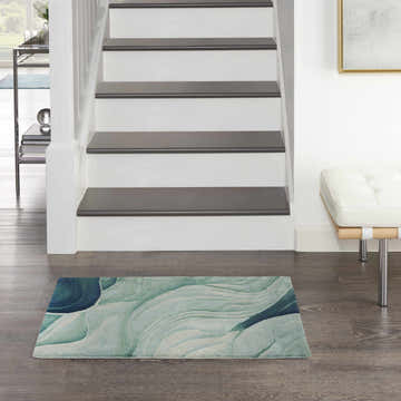 Entryway with Nourison Prismatic Silver Green rug, wood floors, stairs, white walls, and a modern white bench.