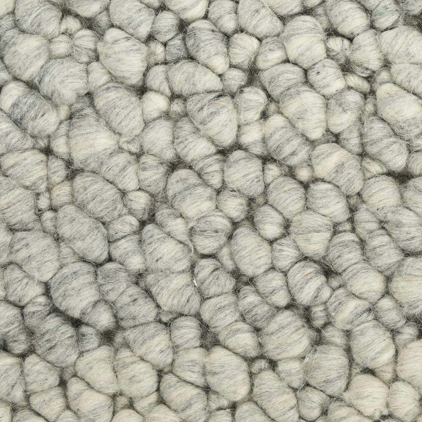Close-up of the Calvin Klein Riverstone rug showing its grey and ivory wool pebble texture.