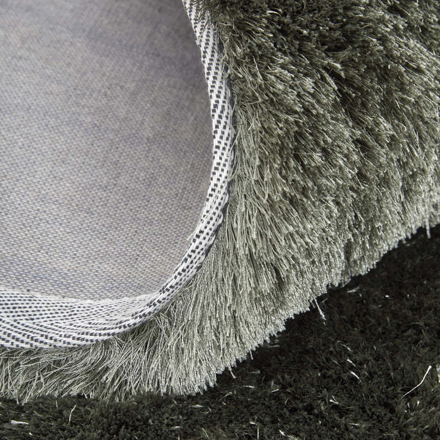 Close up of the Feizy Indochine Modern Solid Green Area Rug showing the shag texture, backing and edge detail. Fold