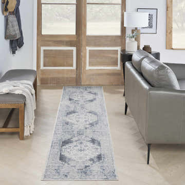 Entryway with grey leather sofa and Nourison Astra Blue Ivory Vintage Runner Rug on light wood floors.
