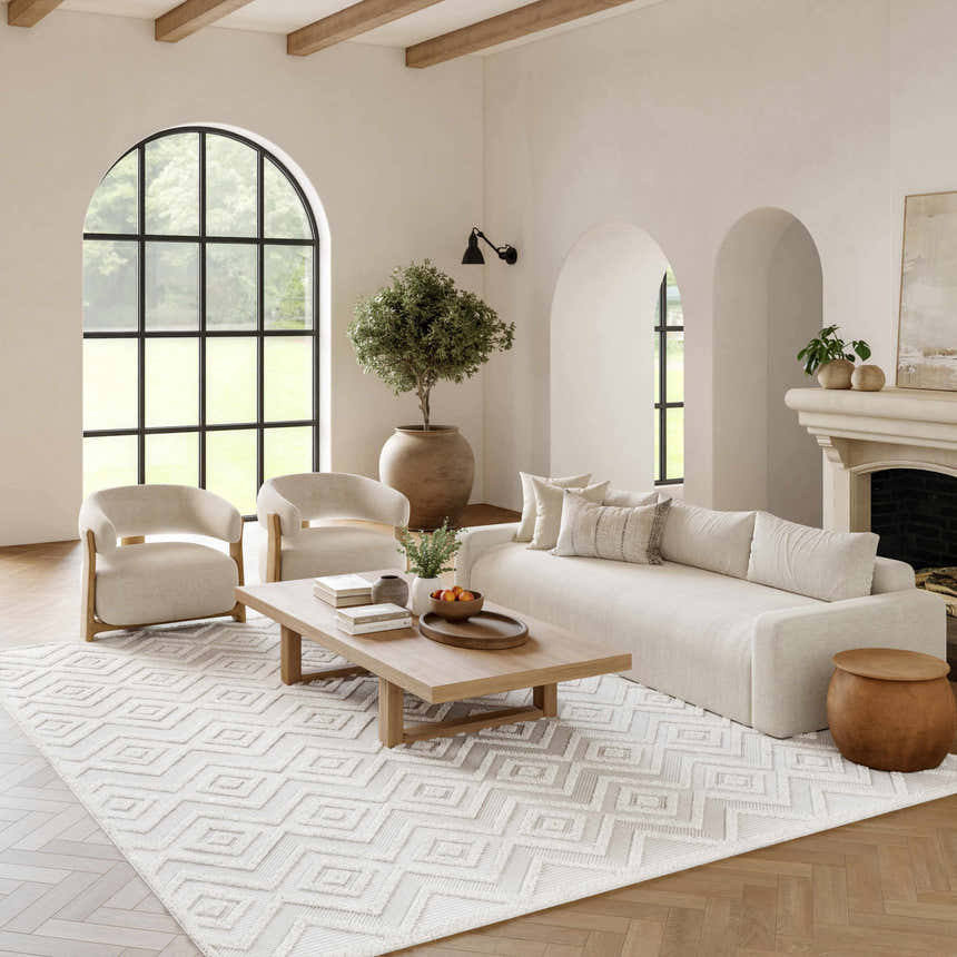 Living room scene with a Nourison Versatile Ivory White rug, sofa, chairs, wood floors, fireplace, and arched windows.
