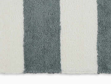 Close-up of Calvin Klein Chicago Shag rug. White and grey stripes, soft shag texture. Modern design.