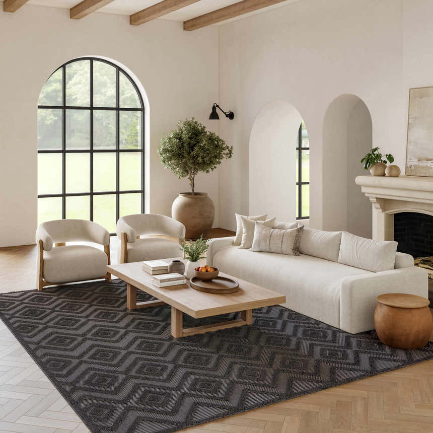 Living room with a Nourison Versatile Charcoal Black rug, light sofa, wood accents, and arched windows. Modern style.