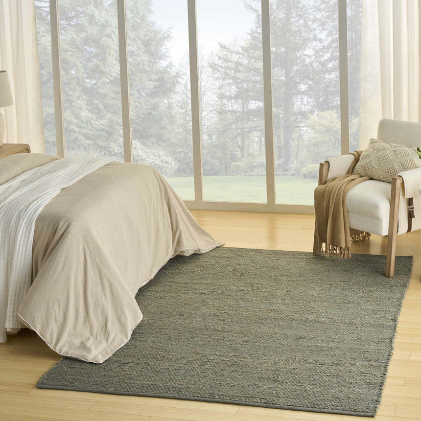 Farmhouse bedroom with a Nourison Natural Jute Sage rug, linen bedding, and a view of a lush green landscape.