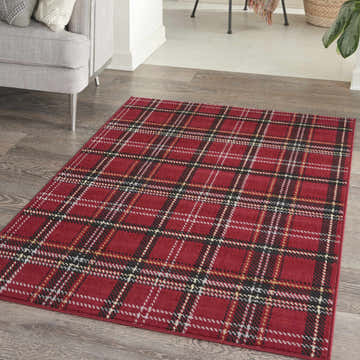 Living room scene with a Nourison Grafix Red Rustic Area Rug featuring a classic plaid pattern on wood floors.