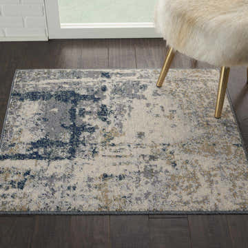 Close-up of the Nourison Artworks Ivory/Navy rug, showcasing its distressed, modern design and wool texture on dark wood floors.
