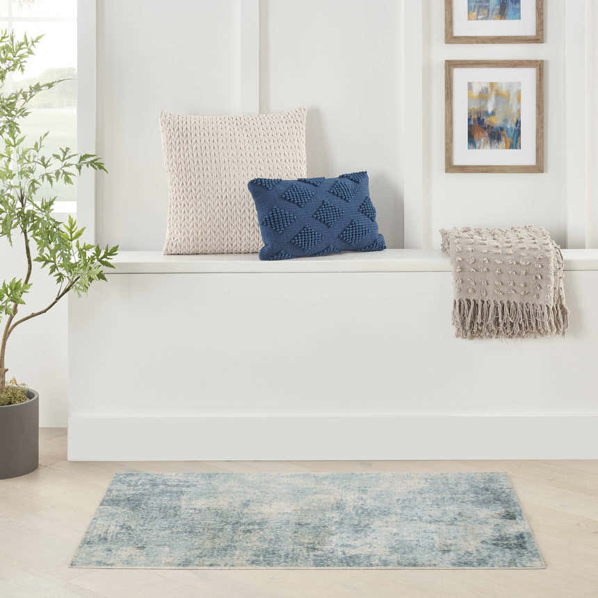 Bright entryway with Nourison Astra Blue Ivory rug, pillows, throw, art, and plant.