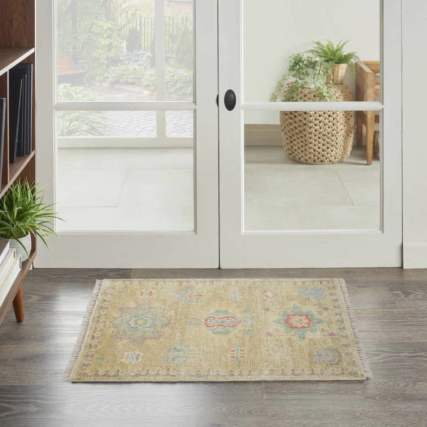 Entryway scene with a Nourison Odessa Sage Vintage Area Rug on gray wood floors near white doors.