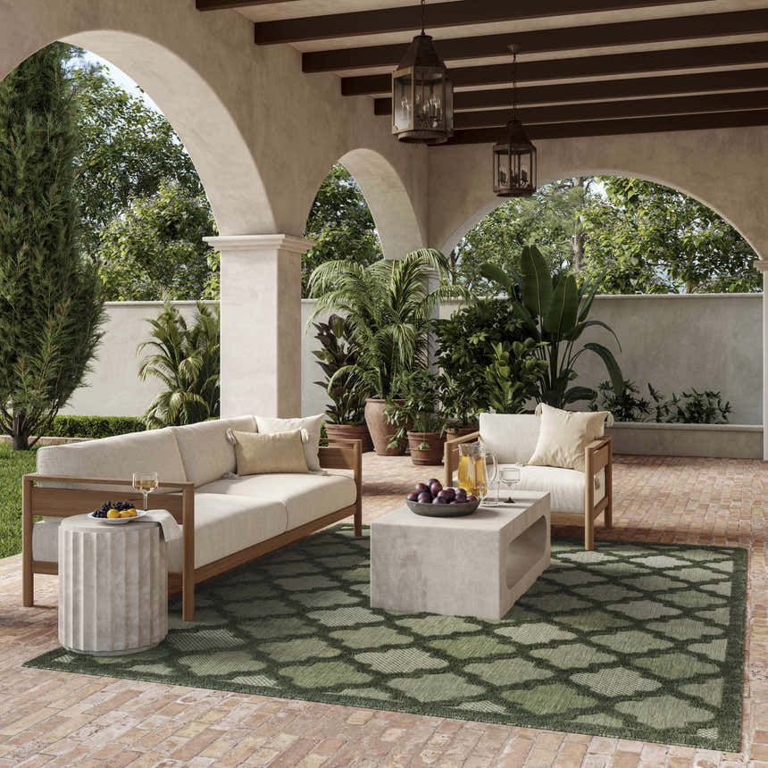 Outdoor patio with beige furniture and a green geometric Nourison Easy Care Area Rug.