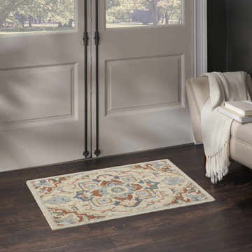 Entryway with Nourison Maison Ivory Rust Vintage Indoor Area Rug on dark wood floor, near white door and beige armchair.