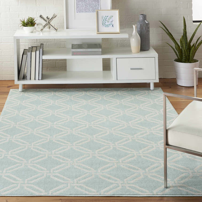 Coastal living room scene with a light blue and white geometric Nourison Jubilant Green rug, white console table and decor.
