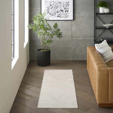 Modern living room with a chestnut leather couch and DKNY Central Park West Ivory rug on dark wood floors.