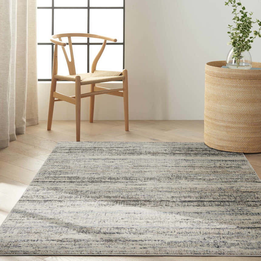 Minimalist room scene with a Calvin Klein Etched Ivory Beige rug, wood chair, woven basket, and light wood floors.