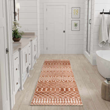White bathroom with Nourison Astra Copper Bohemian runner rug adding warmth and pattern to the light wood floors.
