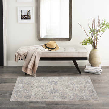 Entryway with Nourison Moroccan Celebration Ivory/Sand rug, bench with blanket, mirror, vase, and gray wood floors.