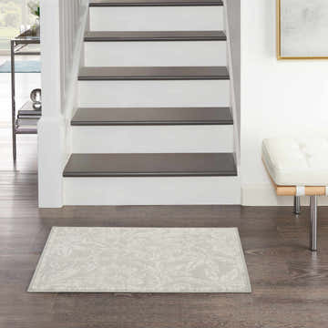 Farmhouse foyer with Nourison Whimsicle Grey rug on dark wood floor, white stairs, and modern bench.