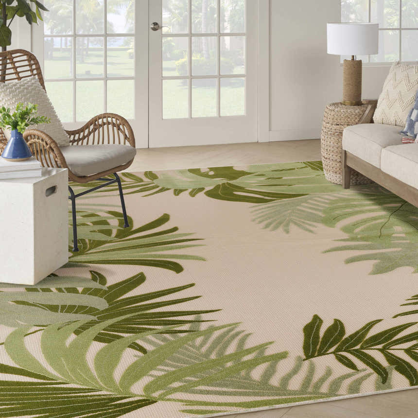 Living room with a Nourison Aloha Ivory Green Outdoor Area Rug, wicker chair, and neutral sofa.