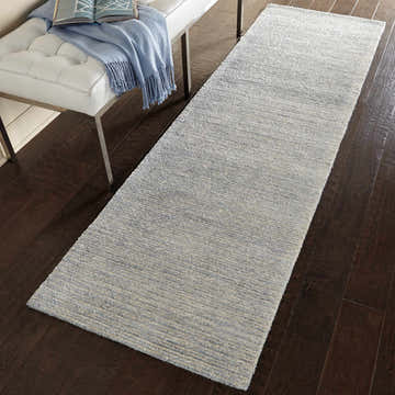 Hallway scene with a Nourison Weston Aquamarine runner rug on dark wood floors, paired with a white leather bench.
