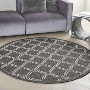 Living room scene with a Nourison Country Side Charcoal round rug, gray sofa, and modern side table.