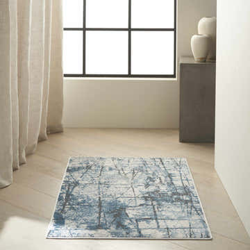 Minimalist room with blue and gray Calvin Klein CK970 Vapor rug, wood floors, neutral drapes, and modern decor.