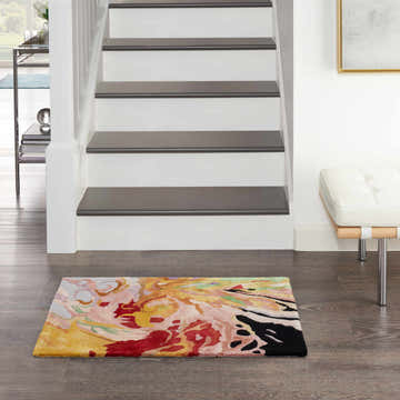 Entryway with a Nourison Prismatic Multicolor rug, wood floors, white stairs, and a modern white bench.