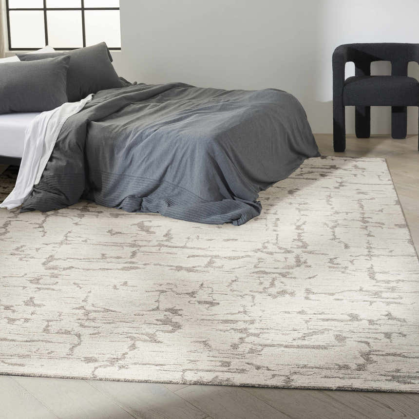 Modern bedroom with gray bedding and Calvin Klein CK009 Sculptural Grey rug, adding subtle pattern and texture.