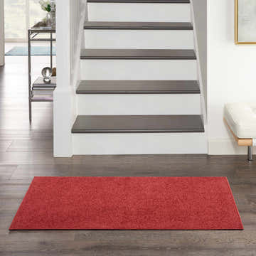 Entryway with a Nourison Essentials Brick Red Outdoor Area Rug on dark wood floors.