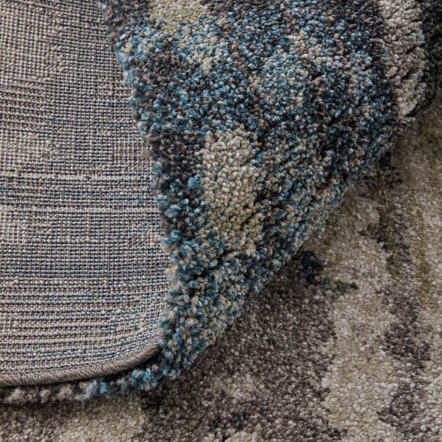 Close-up of Feizy Skyview rug showing gray, black, ivory, and blue abstract pattern and texture. Machine-made weave detail. Fold