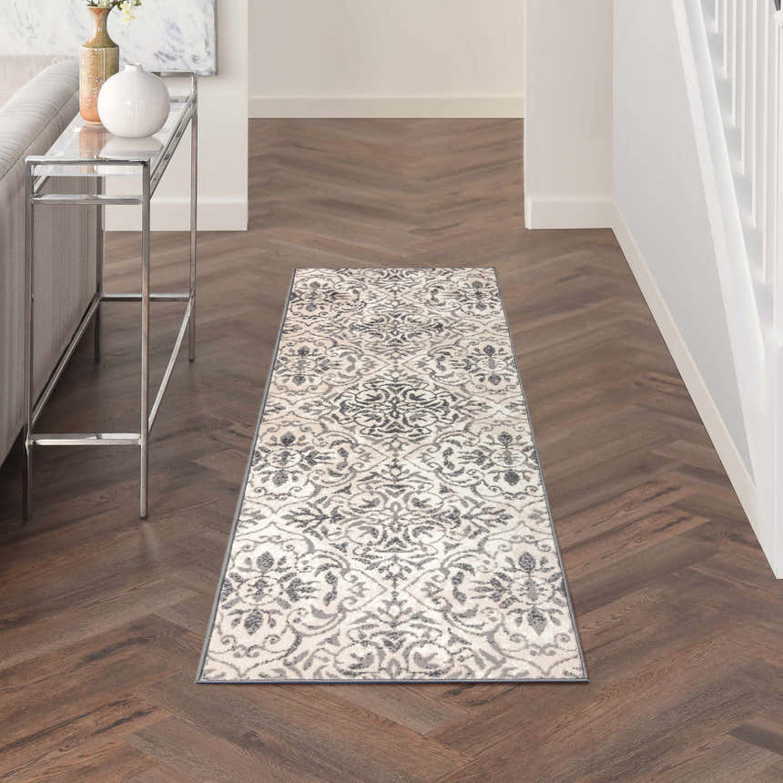 Hallway scene with Nourison Jubilant Ivory Grey vintage runner rug on wood floor. Console table and white walls.