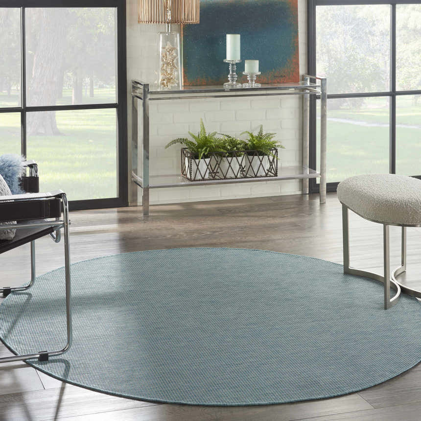 Modern living room with aqua Nourison Positano rug, chrome console table, and large windows.