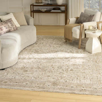Living room scene with a beige curved sofa and Nourison Retreat Beige Vintage Indoor Area Rug.