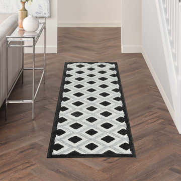 Hallway with Nourison Aloha Black White Modern Area Rug runner on herringbone wood floor.