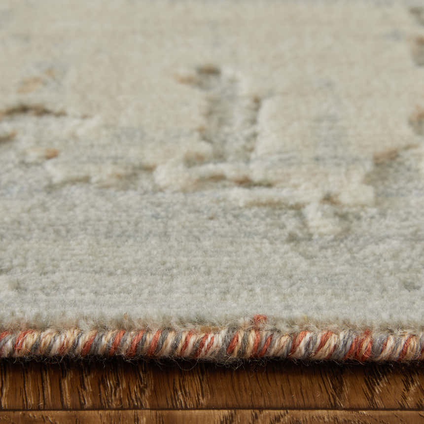 Close-up of the Feizy Jaxson rug showing its gray, ivory, and orange abstract design and textured wool blend. Pile