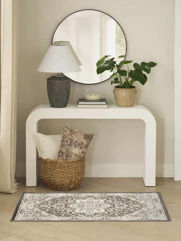 Entryway with white console table, round mirror, and Nourison Dekor Brown Ivory Vintage Area Rug on wood floor.