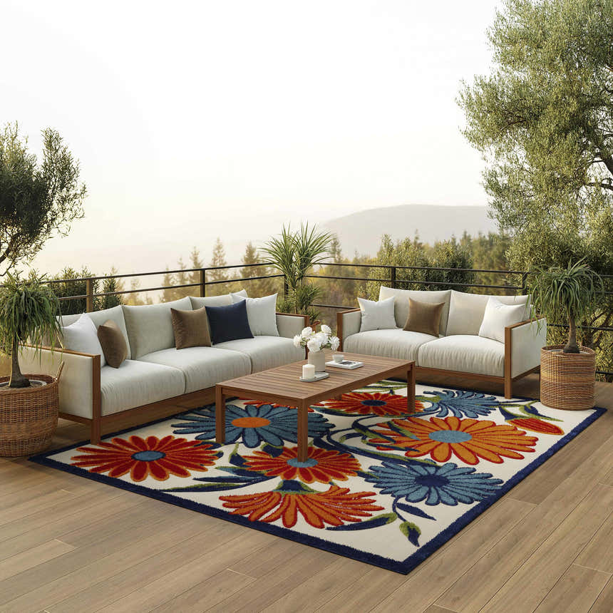 Outdoor patio scene with white sofas, wood table, and Nourison Aloha Multicolor Area Rug with floral pattern.