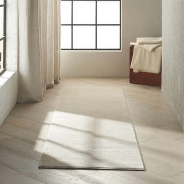 Minimalist room scene with a Calvin Klein Jackson Ivory Grey rug, wood floors, and neutral decor.