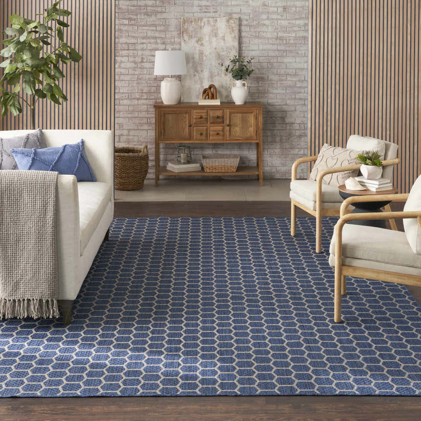 Living room scene with a Nourison Twist Reversible Blue Modern Area Rug, white sofa, wood accents, and a neutral color palette.