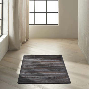 Minimalist room with a black Calvin Klein Home Prairie hair on hide area rug on light wood floors.
