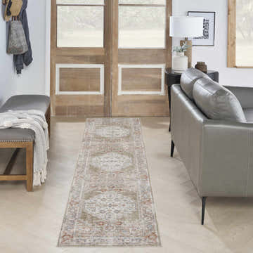 Entryway with a Nourison Astra Sage Multicolor vintage runner rug, gray leather sofa, and wooden bench.