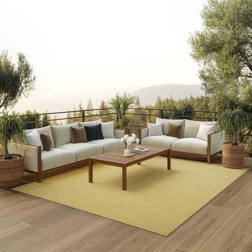 Outdoor patio scene with a Nourison Positano Yellow rug, sofas, wood table, and mountain view.