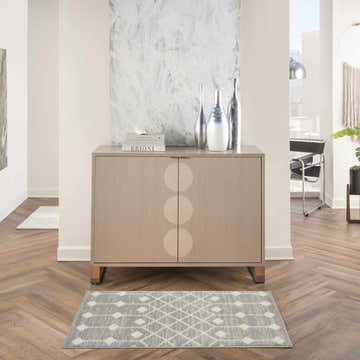 Living room scene with a grey Nourison Grafix Bohemian rug under a modern cabinet with silver vases.