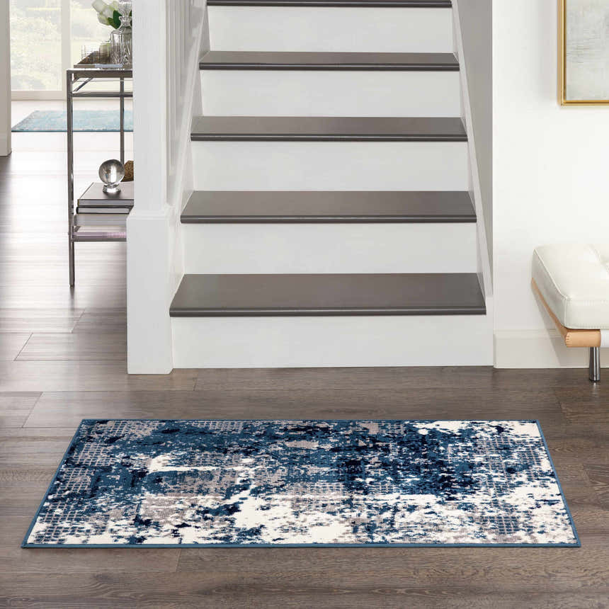 Entryway with Nourison Grafix Navy Blue rug, dark wood floors, white stairs, and modern decor.