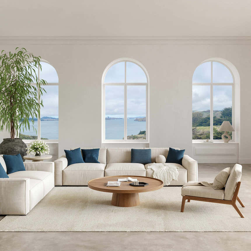 Light-filled living room with Nourison Harmony Ivory rug, neutral sofas, wood accents, and ocean view. Modern coastal style.