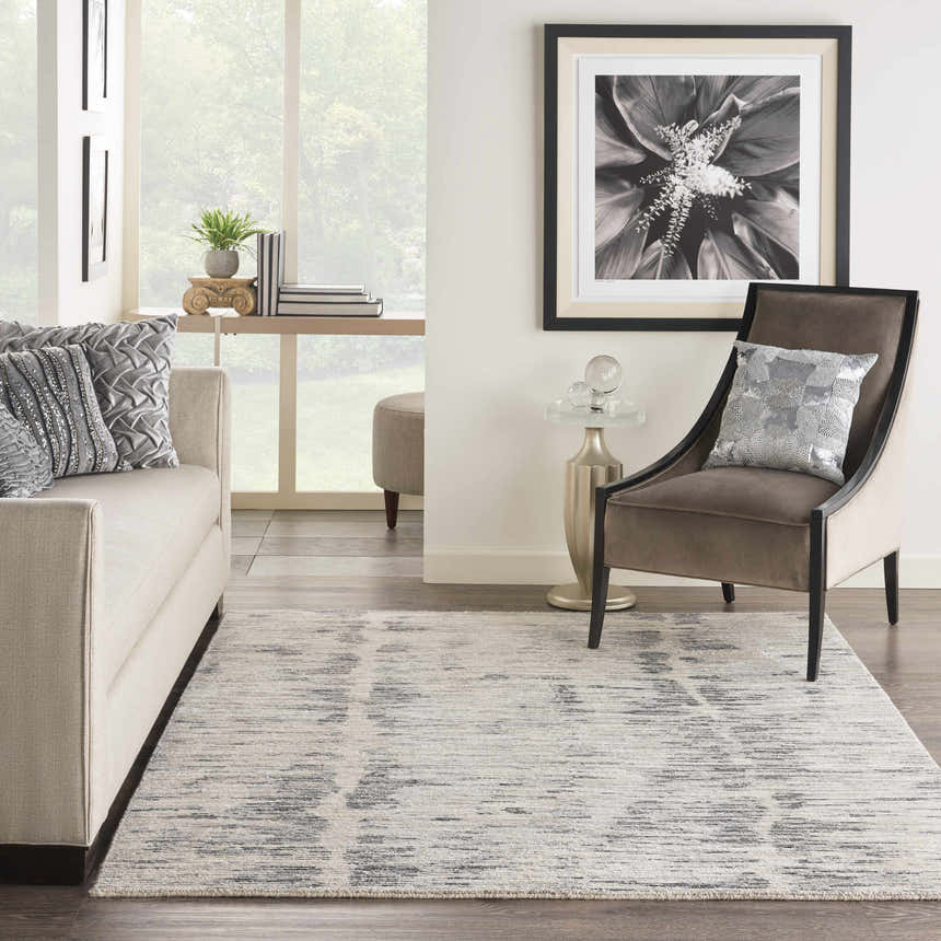 Living room scene with a Nourison OCEAN Cream Charcoal rug, sofa, chair, and modern decor.