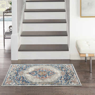 Entryway with Nourison Quarry Blue Grey Vintage Rug, white stairs, and dark wood floors.