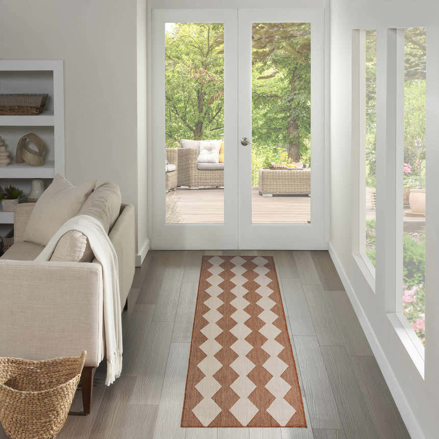 Light-filled entryway with a Nourison Positano Terracotta runner rug, beige sofa, and view of an outdoor patio.