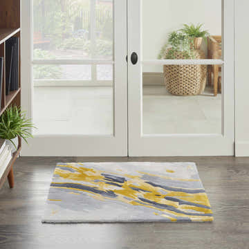 Hallway scene with Nourison Prismatic Grey Gold rug, white doors, wood floors, and bookshelf. Modern, inviting entryway.