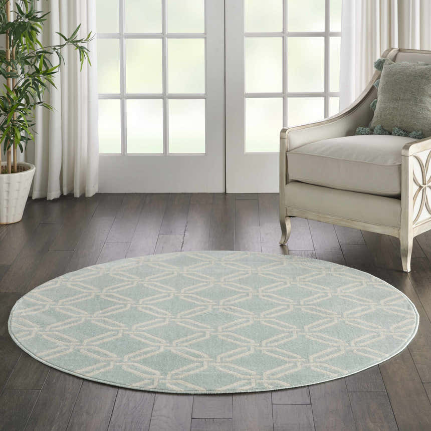 Living room scene with a round Nourison Jubilant Green rug, cream chair, and dark wood floors. Coastal style.
