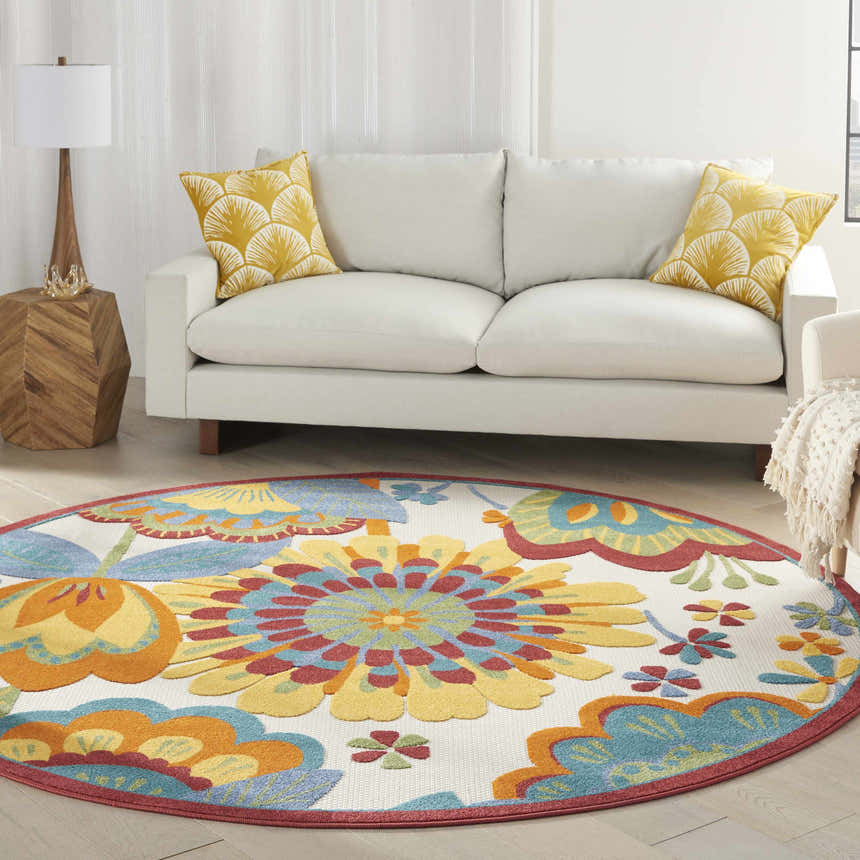 Living room scene with a round Nourison Aloha Multicolor rug, white sofa, and yellow pillows.